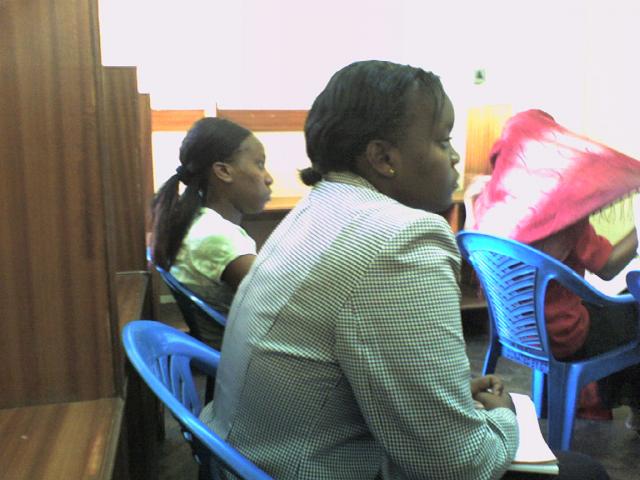 Mercy (Project Assistant) and Monica (friend and supporter) look on as Violet speaks