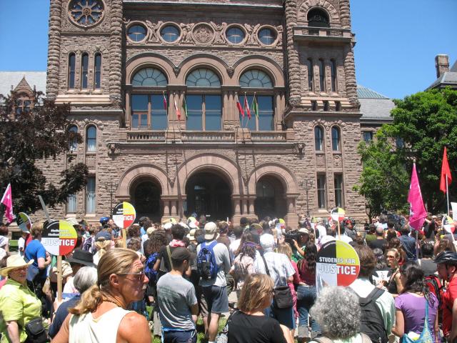 Speakers gather outside a canadian government building, Queens Park.
