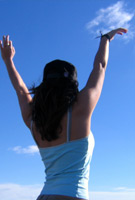 Young woman reaching up to sky